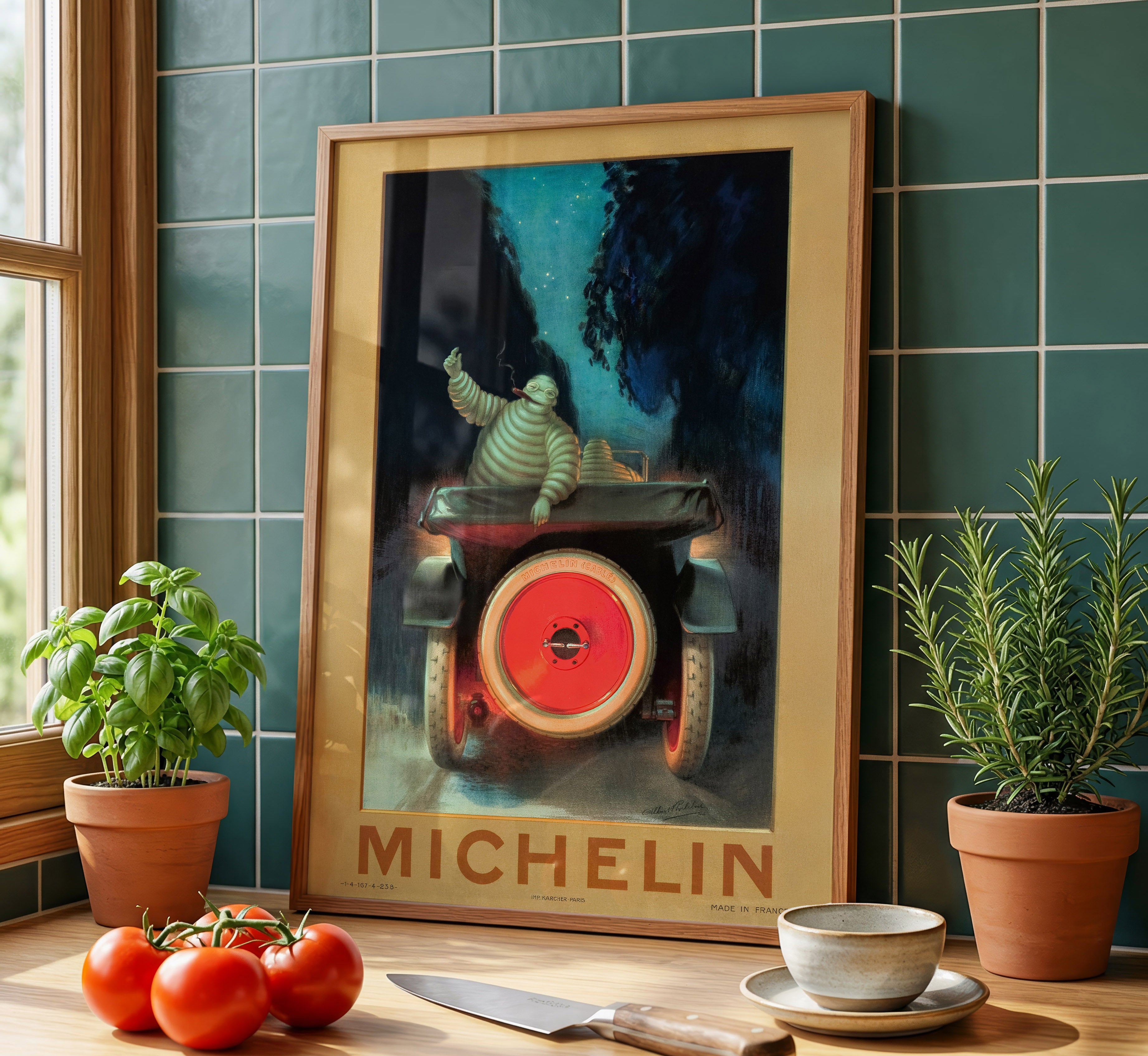 Vintage Michelin Bibendum motoring poster displayed against a dark green tiled wall in a design-focused kitchen interior.