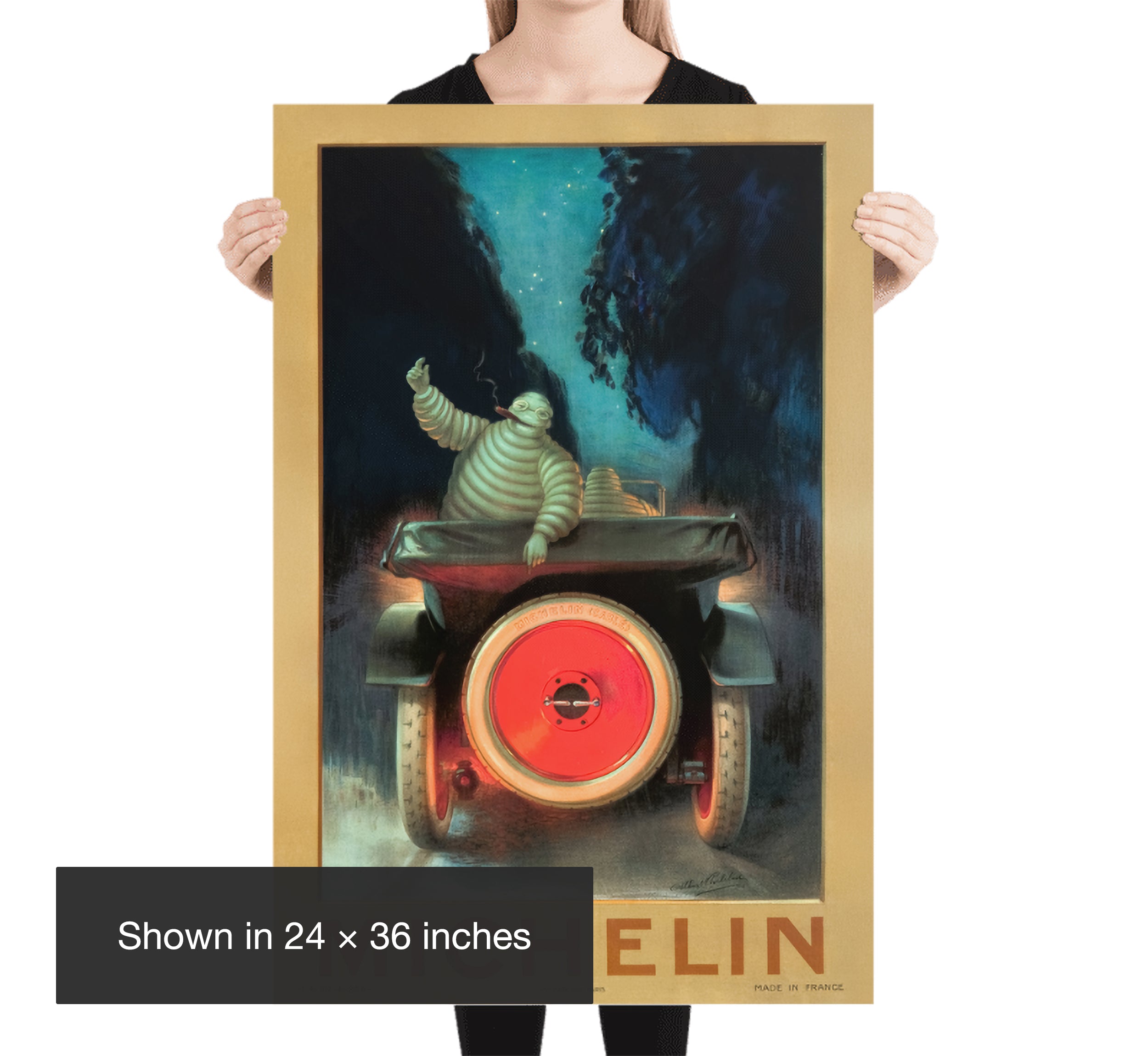 Woman holding a 24 × 36 inch Michelin Bibendum Night Drive poster, providing a clear size and scale reference for the vintage automotive print.
