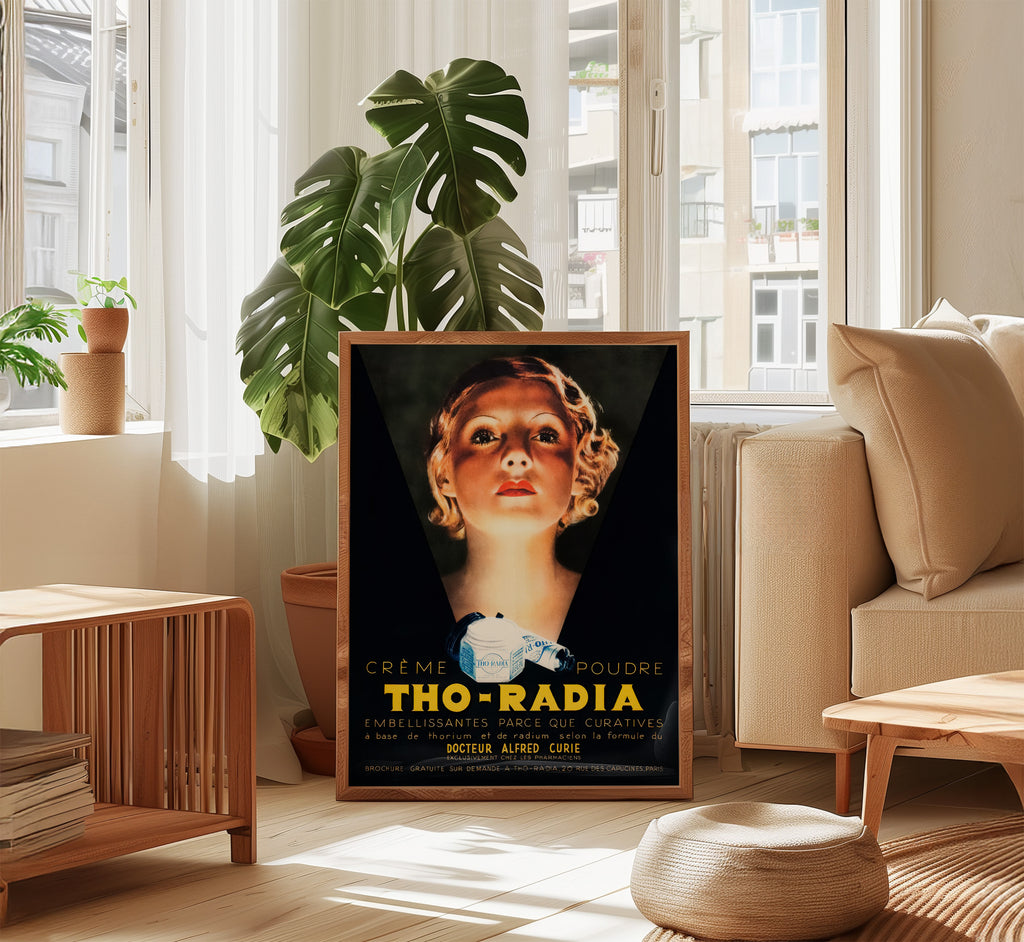 Framed Tho-Radia 1930s French beauty poster displayed in a bright modern living room beside a large monstera plant.